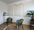 room with two chairs, round rug, white cabinet, plant, three large white boards on wall