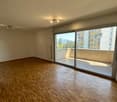 Spacious living room with hardwood flooring, large windows providing natural light, and access to a balcony or terrace.
