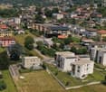 This image shows a residential area in a mountainous region. The area is densely populated with multi-story apartment buildings and houses. The buildings have a mix of architectural styles and colors, with some having red tile roofs. The area is surrounde