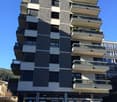 high rise residential building, multiple balconies, multiple parking spaces in front