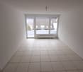 Completely empty room with white tiled floor, white walls, and a large glass door leading to a balcony.