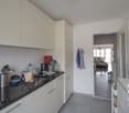 modern kitchen, marble countertop, white cabinets, modern appliances, sink, open door to hallway