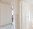Empty room with white walls, white tiles, white doors, and wooden floor.