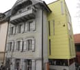Multi-story hotel building, metal facade, balcony on the second floor, glass windows, glass doors