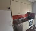 kitchen with stainless steel countertop, stainless steel sink, electric cooker, dishwasher, fridge, gas stove, cabinets, tiled wall, glass door to balcony