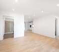 Empty room with wooden floor, white walls, and ceiling lights.