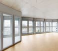Large windows, wooden floor, concrete ceiling, balcony access