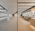 Empty office space, concrete floor, white walls, glass windows, waiting area with chairs and plants