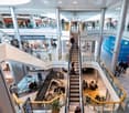 Open shopping mall, multiple levels, escalators, food court, several shops and cafes.