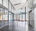 modern building with tiled flooring, large glass walls, elevators, and glass doors