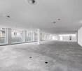 Empty room with white walls, gray carpet, large windows, and ceiling with air vents