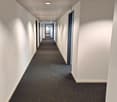 Empty hallway with white walls, gray carpet, and ceiling lights