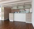 modern kitchen with wooden floors, white walls, wooden cabinets, glass cabinets, island countertop, stainless steel appliances