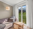 leather couch, wooden table, floor lamp, balcony, large window, view of mountains