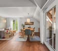 open living room with dining area, wooden floor, white walls, large windows, balcony, view of the outside