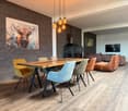 Dining room with wooden table, 6 chairs, brick wall, fireplace, TV, couch, artwork