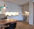 modern kitchen with wooden table, white cabinets, stainless steel appliances, wooden floor