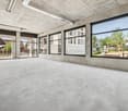 Large open space with concrete floors, high ceilings, and large windows overlooking a green outdoor area
