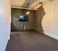 empty room with brick wall, mounted TV, hanging lamps, and white and brown floor