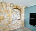 a kitchen with a stone wall and a double oven