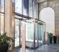 spacious entrance with high ceiling, large glass doors, granite floors, glass walls, two large indoor plants