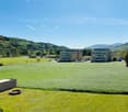 large green field, two buildings in the background, mountains in the distance