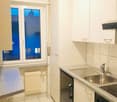 modern kitchen with white tiles, white cabinets, stainless steel sink, gas stove, window with view