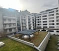 Several buildings with multiple balconies, green rooftop, glass windows