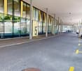 Covered walkway with glass walls, concrete floor, yellow parking lines, parked cars