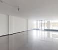 Large open space with white walls, high ceilings, and large windows providing ample natural light. The floor is covered with shiny, reflective tiles. The space appears to be a commercial or office area, ready for customization and furnishing.