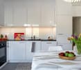 modern kitchen with white cabinets, black countertops, modern appliances, dining table with fruits, flowers in vase