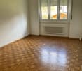 empty room, wooden parquet floor, white walls, large window, white radiator