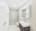 modern bathroom, white tiles, glass door, large mirror, toilet, sink, shower