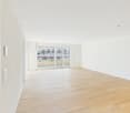 Empty room, wooden floors, sliding glass doors leading to balcony