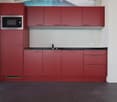 modern kitchen with red cabinets, black countertops, integrated microwave, sink with faucet, electrical outlet