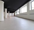 Empty room with white tiles, white pillars, black ceiling, large windows
