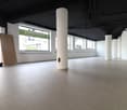 Empty room with tiled floor, white walls, large windows, and two central pillars.