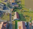 houses, paved road, green grassy fields, trees, parked cars, solar panels