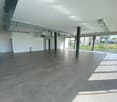 large room, tiled floor, white walls, large windows, metal beams, metal pipes