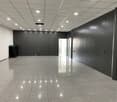 Empty room with gray tiled floor, white ceiling, gray walls, and a black object on the left side.