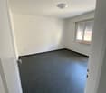 Empty room, white walls, black tile floor, a window with shutter, a ceiling light