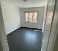 Empty room with white walls, black tiled floor, large window with view outside, ceiling light