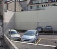 a gated parking lot with four cars parked in it and a bicycle parked in front of the fence