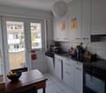 White cabinets, black countertop, black oven, wooden table, bananas in bowl, glass door