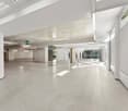 Empty room with white walls, white floor, and white ceiling. There are windows on the right side and exit signs on the ceiling.