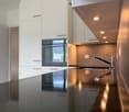 Modern kitchen with white cabinets, black countertops, and stainless steel appliances.