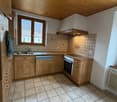 A kitchen with wooden cabinets, a sink, a faucet, a dishwasher, an oven, tiled floor, ceiling lights, a window, and a radiator.