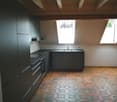 Modern kitchen with black cabinets, hexagonal tiled floor, and a sink with a faucet.