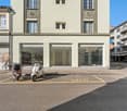 2 story building, white exterior, glass windows, 3 glass doors, bicycles parked in front, stop sign, parking space