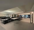 Spacious office space with glass walls, grey carpet, large tables and chairs, and desk lamp